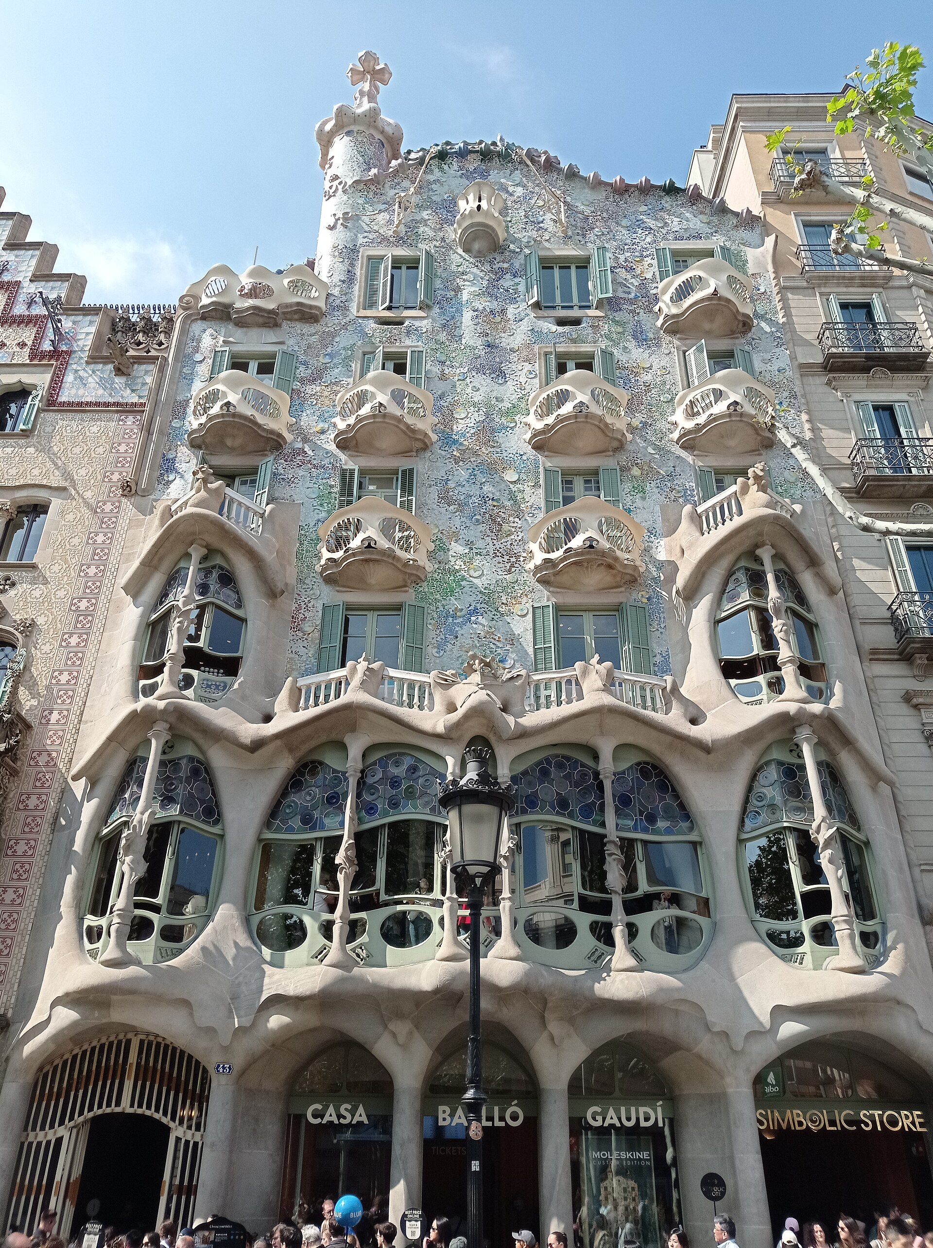 Fachada de Casa Batlló en el Passeig de Gràcia: mosaico, balcones óseos, farola y taquilla en planta baja.
